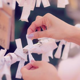 おみくじを枝に結ぶ女性の手元