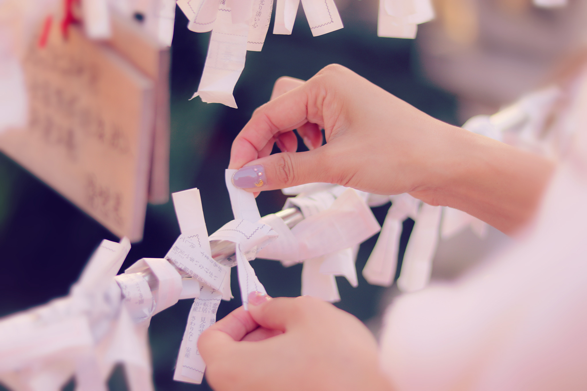 おみくじを枝に結ぶ女性の手元