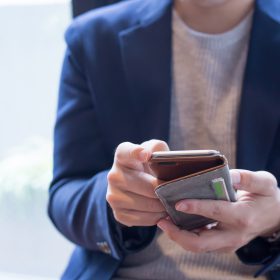 結婚相談所のお相手データベースをスマホでみる青いジャケットの男性