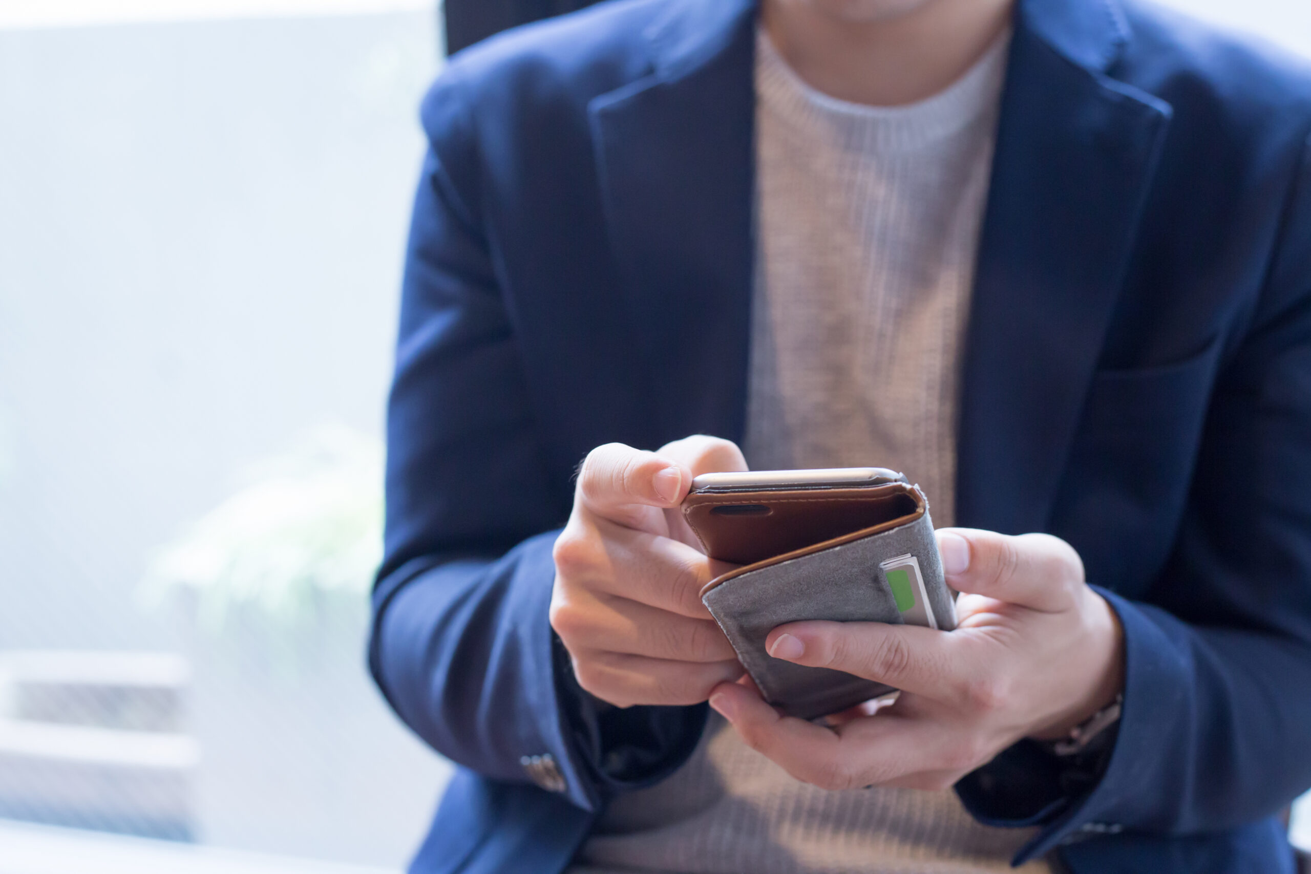 結婚相談所のお相手データベースをスマホでみる青いジャケットの男性