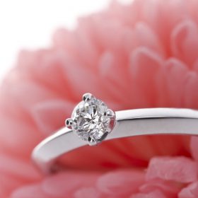 ピンクの花をバックに置かれたエンゲージリング