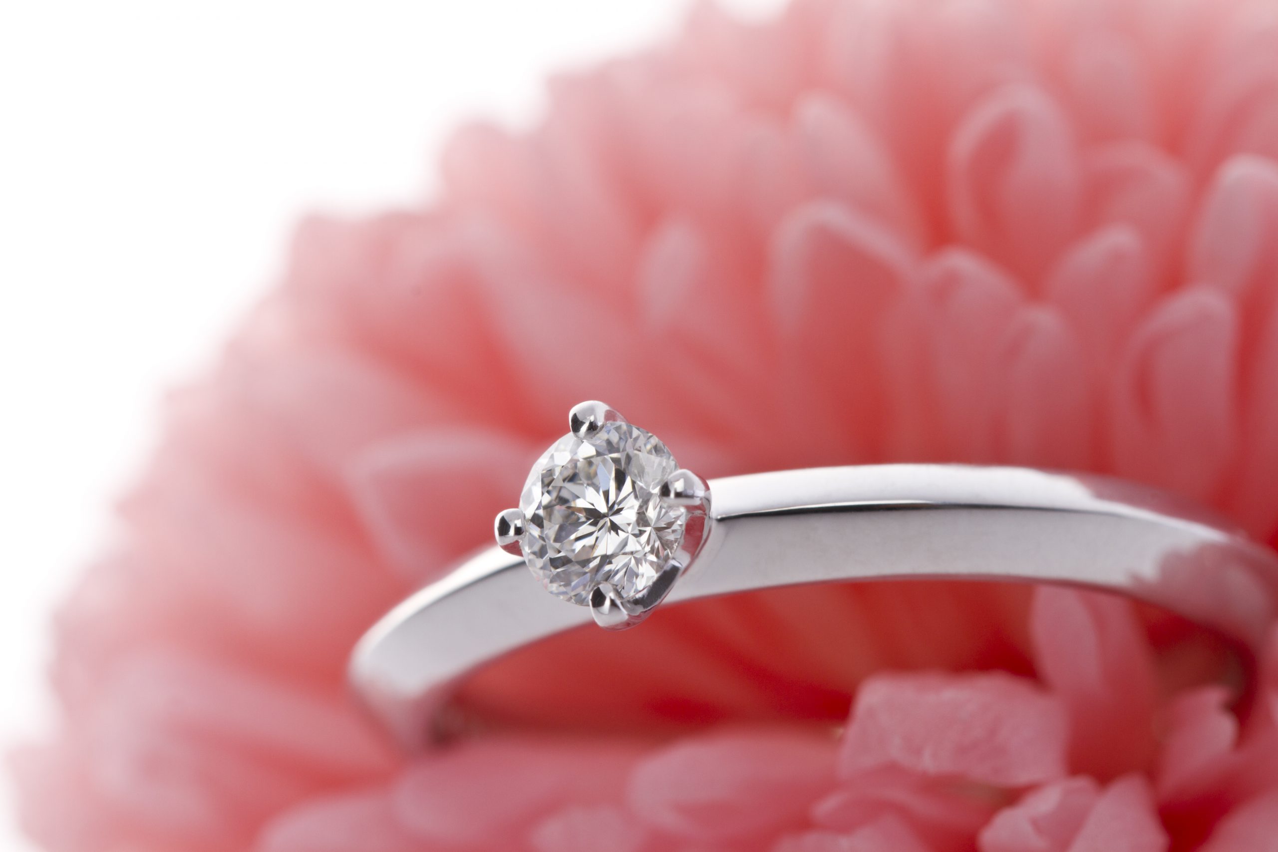 ピンクの花をバックに置かれたエンゲージリング