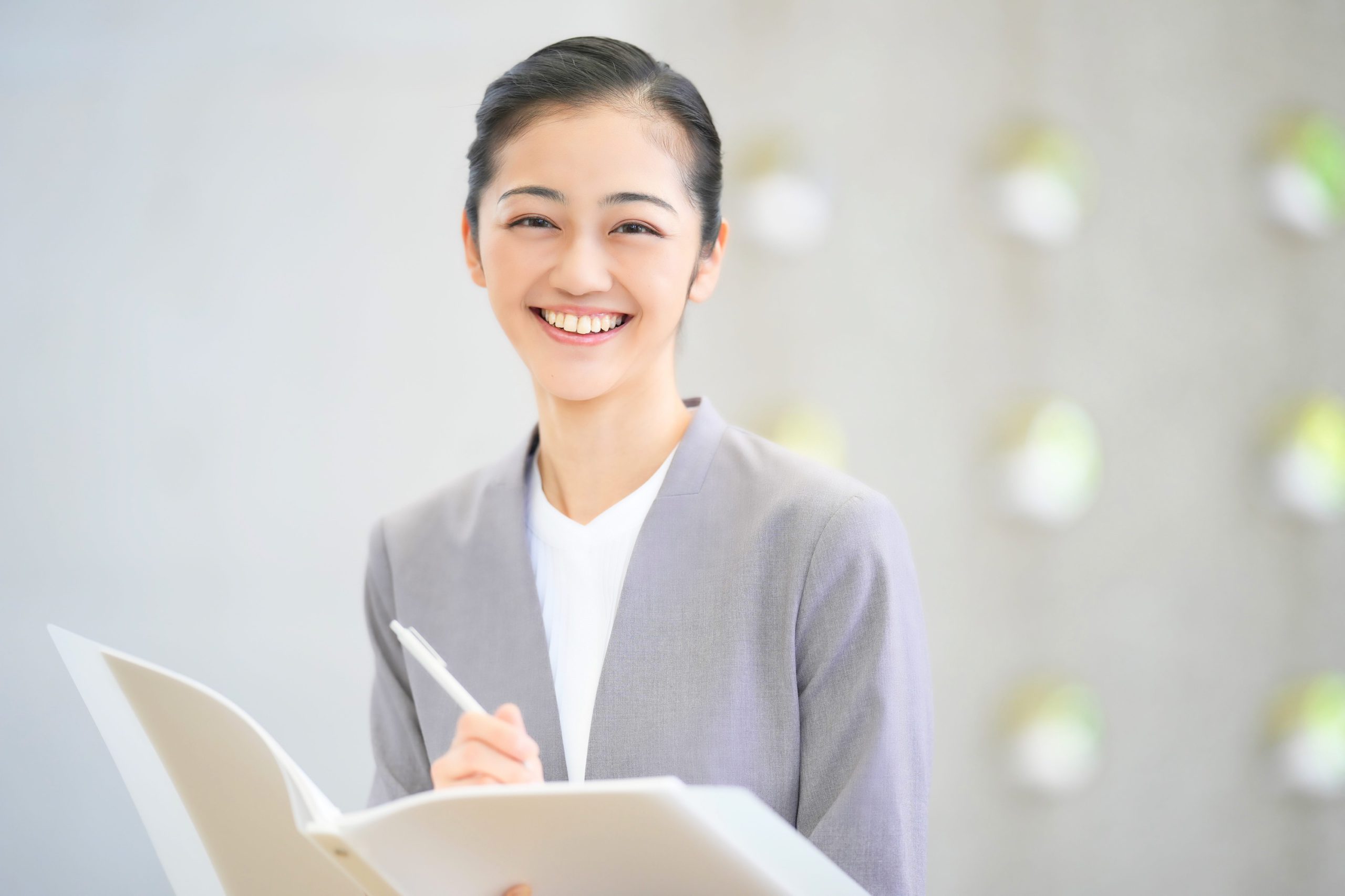 グレーのスーツを着た笑顔の若い女性