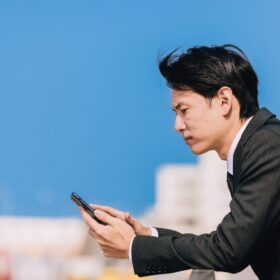 携帯を見ながら考え込むスーツ姿の男性