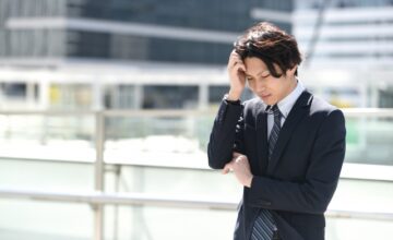 テラスで考え事をするスーツ姿の婚活男性