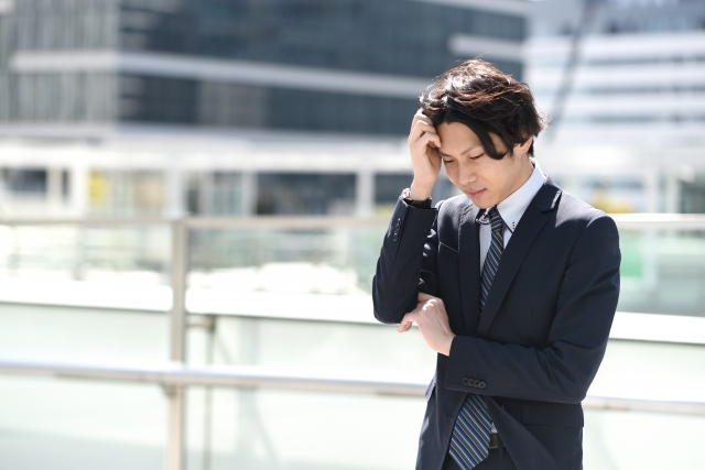 テラスで考え事をするスーツ姿の婚活男性