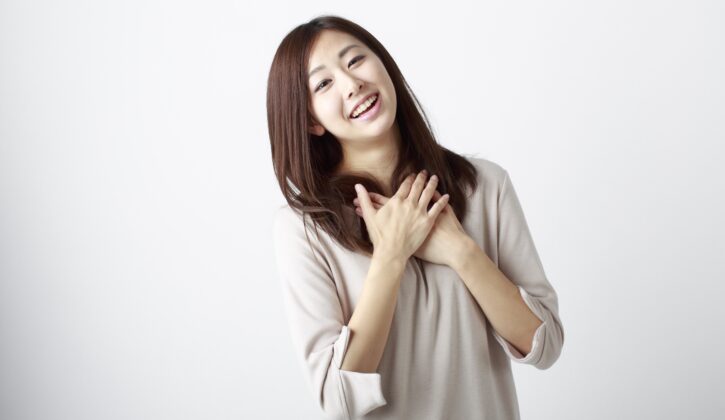 胸に手を当ててホッとした表情の若い女性